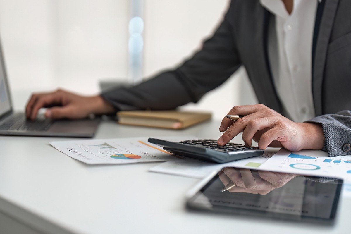 Innovative-management-alternatives-accounts-receivable Healthcare billing specialist reviewing financial reports and calculating accounts receivable data on a laptop in a medical office.
