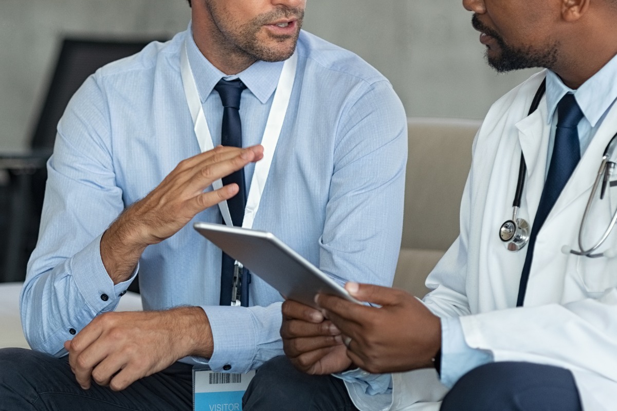 Healthcare administrator and medical provider reviewing billing and practice management information on a tablet in a medical office.